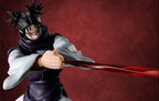 A collectible action figure of the character Choso from Jujutsu Kaisen, captured mid-action with his finger pressed onto the string of a large red bow, set against a textured dark red background.
